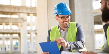 man in construction hat happily speaking with coworkers