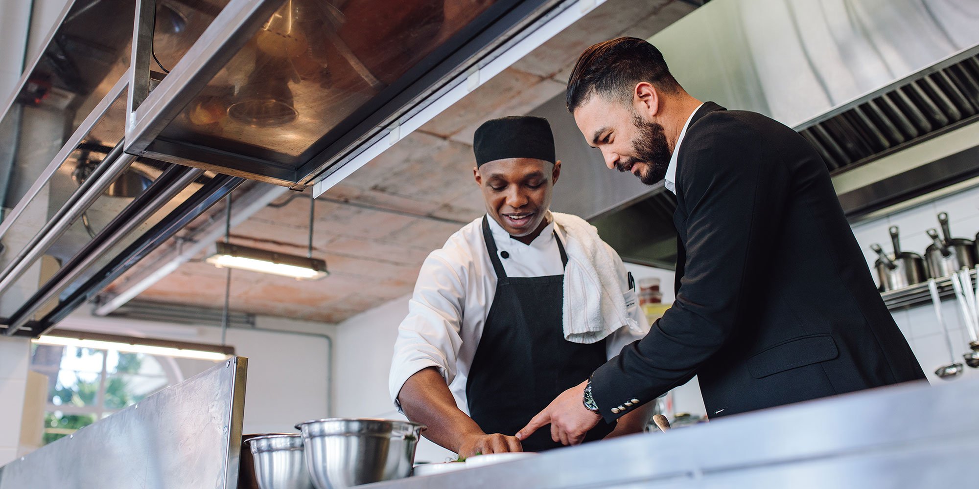 A restaurant manager and head chef looking happily over a menu.