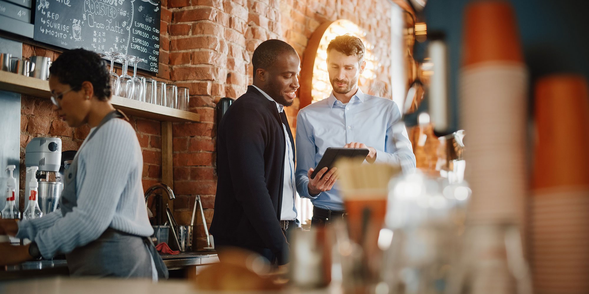 Restaurant manager and staff looking at register point-of-sale system